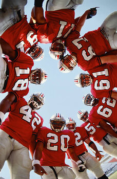 Umjetnička fotografija Football team in huddle, low angle view
