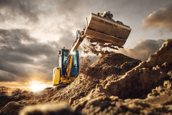 Billede på lærred Excavator scooping dirt in front of a dramatic sky
