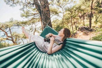 Billede på lærred Woman relaxing in hammock and playing