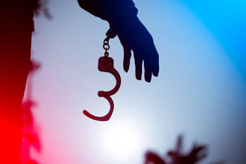 Póster A prisoner behind bars with hands cuffed