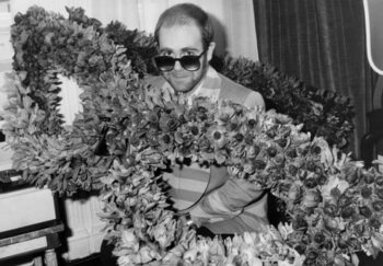 Tableau sur toile English Singer Elton John at his Arrival in Paris : Bunch of Flowers in The Shape of Glasses He Wears, December 1St, 1976