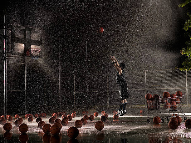 Levně Plakát, Obraz - Man shooting basketball at night in, Adam Weiss, 40 × 30 cm