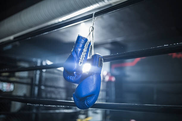 Levně Plakát, Obraz - Boxing gloves hanging in boxing ring, Westend61, 40 × 26.7 cm