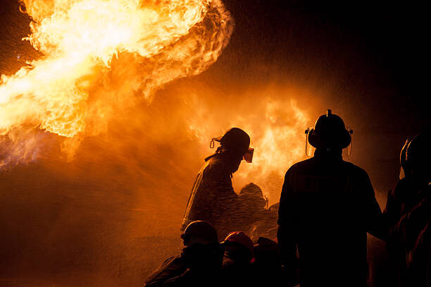 Levně Plakát, Obraz - Silhouette of Firemen fighting a raging fire, Thanarak, 40 × 26.7 cm