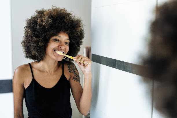 Levně Plakát, Obraz - Multiracial woman brushing teeth in bathroom, Drazen_, 40 × 26.7 cm