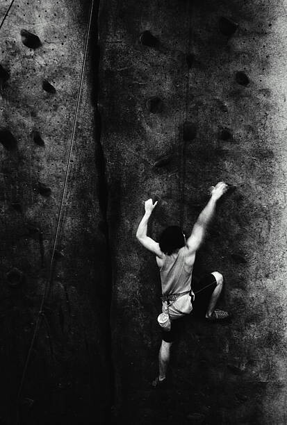 Fotografie Man rock climbing, indoors, rear view , Joe McBride, 26.7 × 40 cm