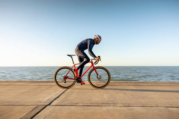 Levně Plakát, Obraz - Cyclist on path by sea, Compassionate Eye Foundation/David Oxberry, 40 × 26.7 cm