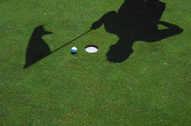 Levně Plakát, Obraz - SHADOW OF GOLFER & FLAG AT HOLE WITH BALL, Grant Faint, 40 × 26.7 cm