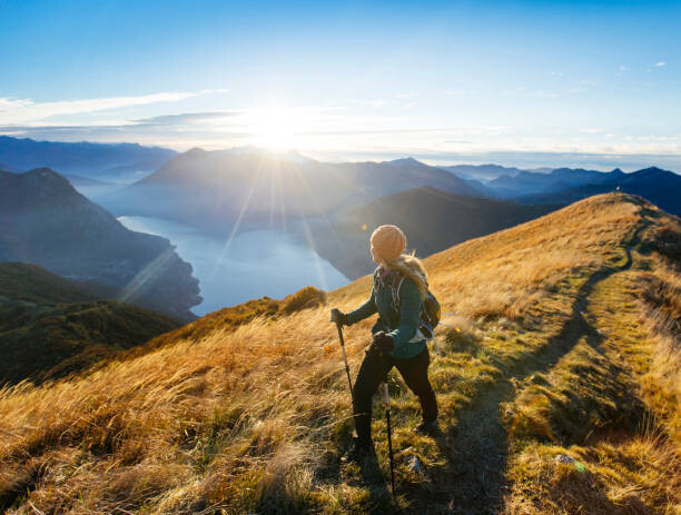 Plakát, Obraz - Woman hikes along ridgecrest above lake, valley, Milo Zanecchia/ Ascent Xmedia, 40 × 30 cm