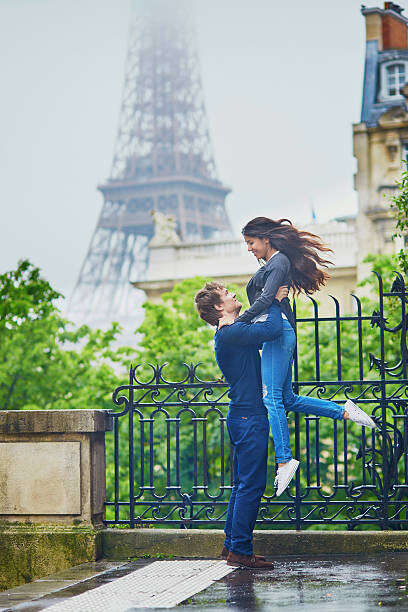 Levně Plakát, Obraz - Happy young couple in front of the Eiffel tower, encrier, 26.7 × 40 cm