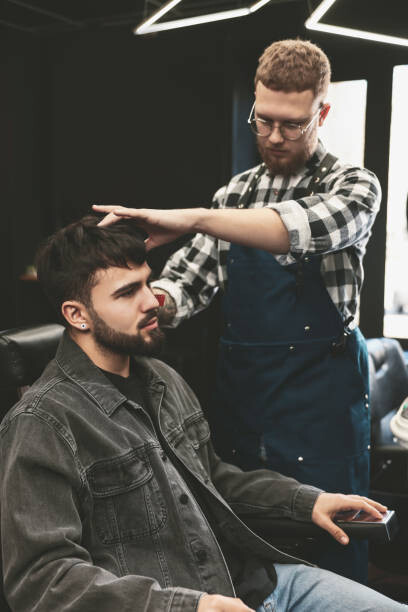 Levně Plakát, Obraz - Professional hairdresser working with bearded client, Liudmila Chernetska, 26.7 × 40 cm