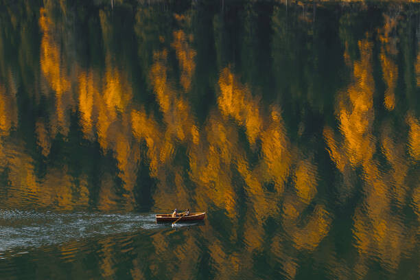 Fotografia artistica Aerial view of boat sailing by beautiful autumn lake with forest reflection in water