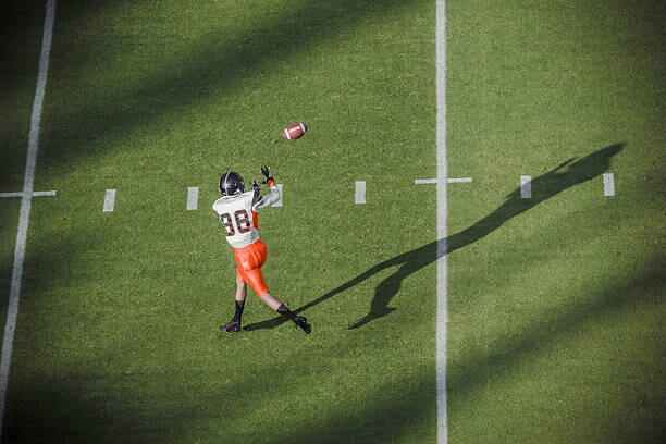 Художествена фотография American football player catching a pass.