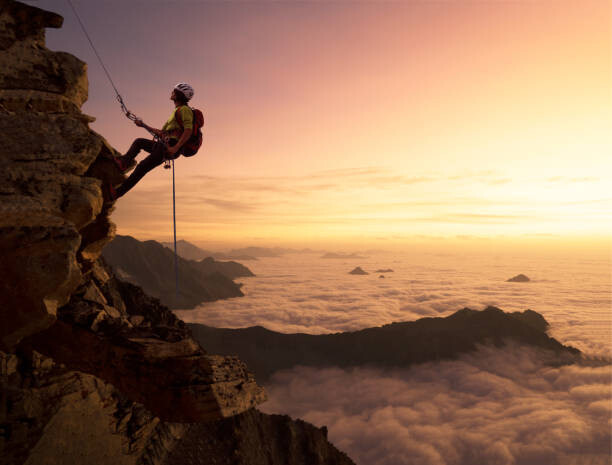 Художествена фотография Climber on a rocky wall over clouds