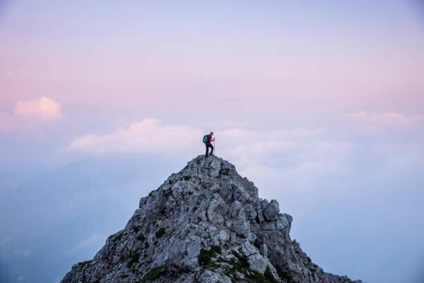 Fotografia artystyczna Hiker man on the top of mountain during twilight