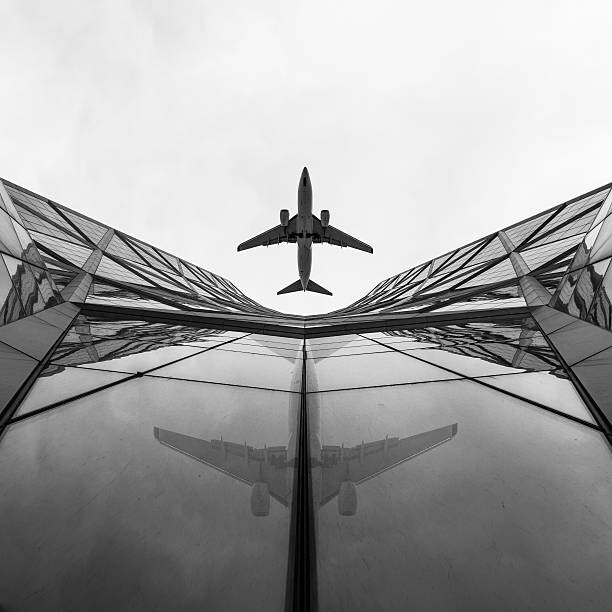 Photographie artistique Jet airplane passes overhead skyscrapers