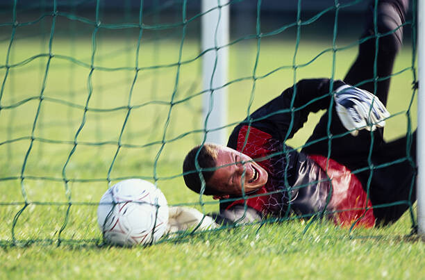 Umjetnička fotografija Male football goalie lying on field,