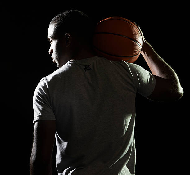 Konstfotografering man holding basketball on shoulder