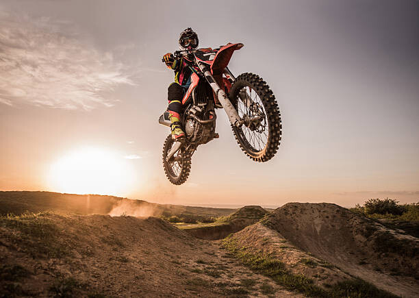 Művészeti fotózás Motocross rider performing high jump at sunset.
