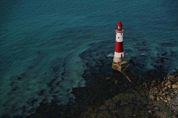 Umělecká fotografie Red and white lighthouse on the sea shore.