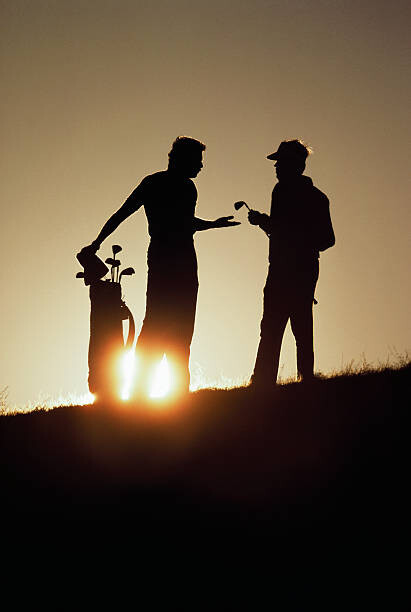 Photographie artistique Silhouetted Golfers Discussing Strategy