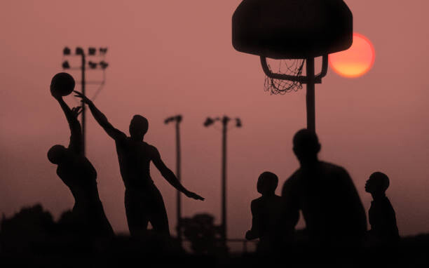 Umelecká fotografie Young men playing basketball at sunset.