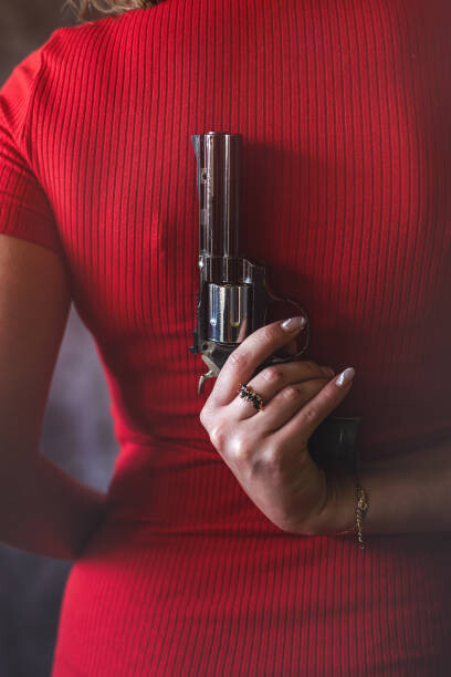 Kunstfotografi young woman in red dress holding gun pistol