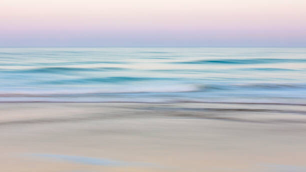 Two women doing yoga on the beach at sunrise