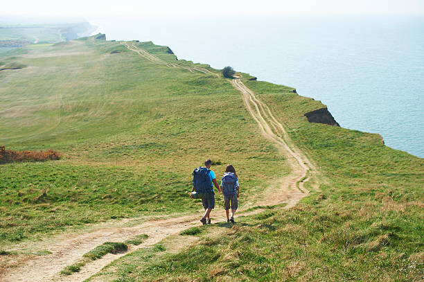 Obraz na plátne Male and female walking along path on cliff top