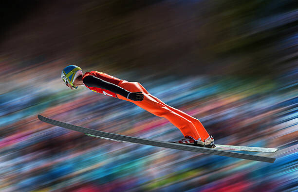 Schilderij op canvas Ski jumper in mid-air against blurred background