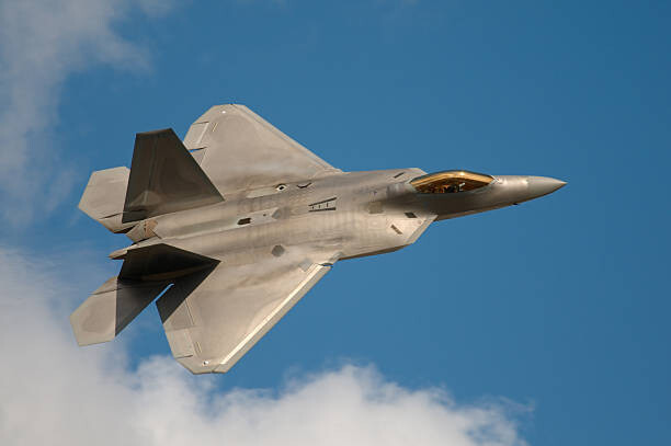 Behang F22 Raptor Jet Fighter flying in the sky