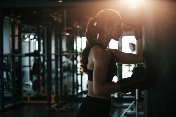 Fototapet Tired woman wearing boxing gloves leaning