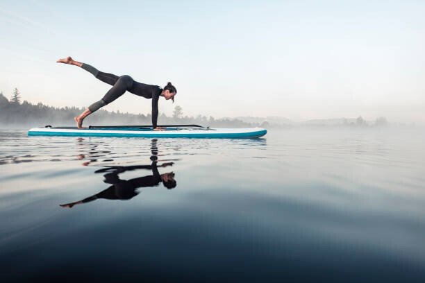 Fototapete Woman practicing paddle board yoga on