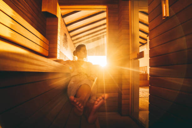 Fototapeta A young woman relaxing in an eco wooden sauna