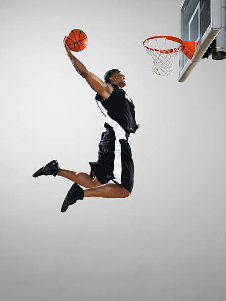 Fototapeta Basketball player dunking ball, low angle view