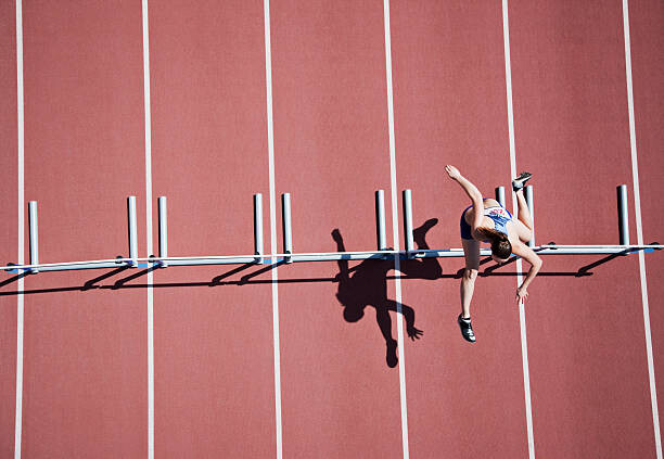 Fototapeta Runner jumping hurdles on track