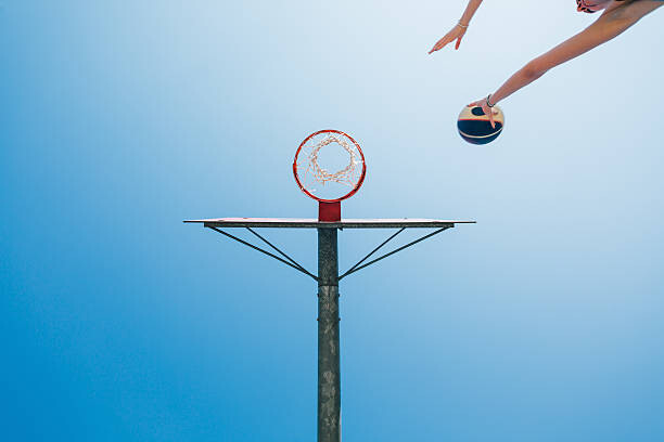 Fototapeta Woman shoots for goal in the basketball court