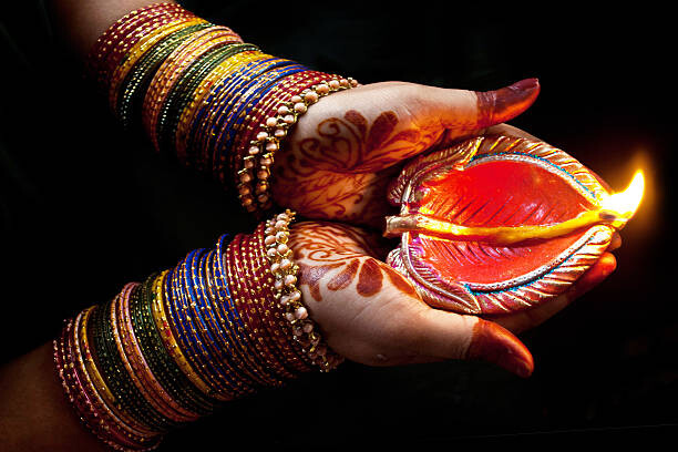 Fototapeta Woman with lit earthen lamp at Diwali festival