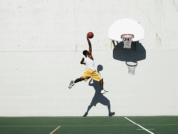 Fototapeta Young man shooting at basketball hoop