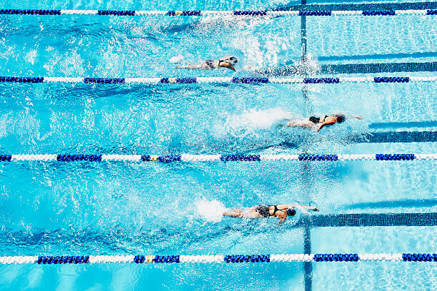 Obraz na plátně Competitive swimmers racing in outdoor pool