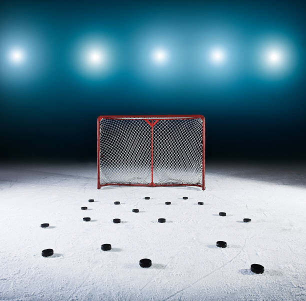 Obraz na plátně Ice hockey goal surrounded by pucks.