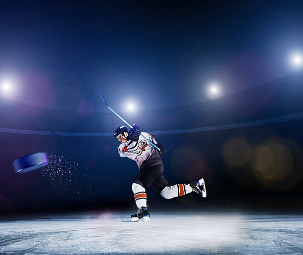 Obraz na plátně Ice hockey player shooting puck.