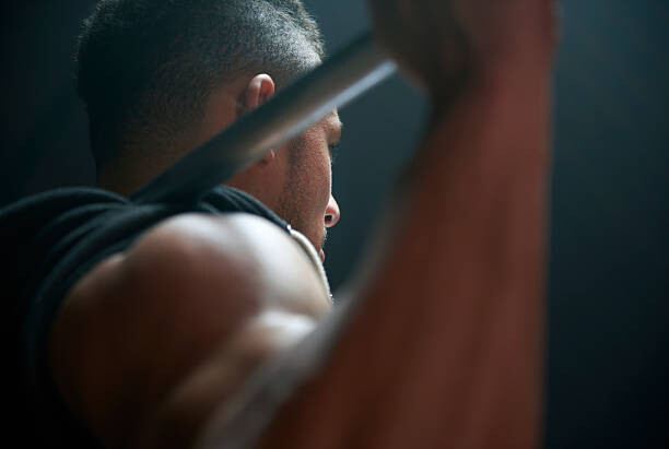 Obraz na plátně Male athlete lifting weight bar black background