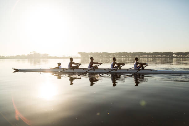 Obraz na plátně Mixed race rowing team training on a lake at dawn