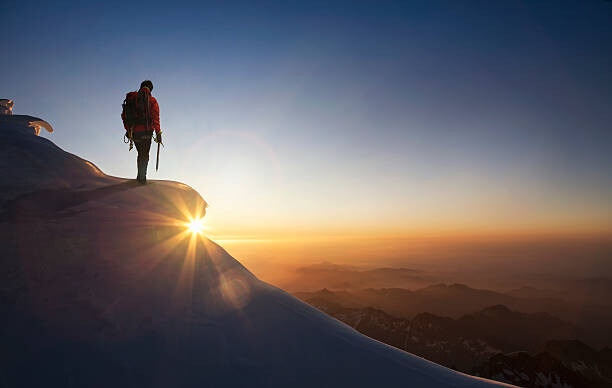 Obraz na plátně Climber on a snowy range at sunset
