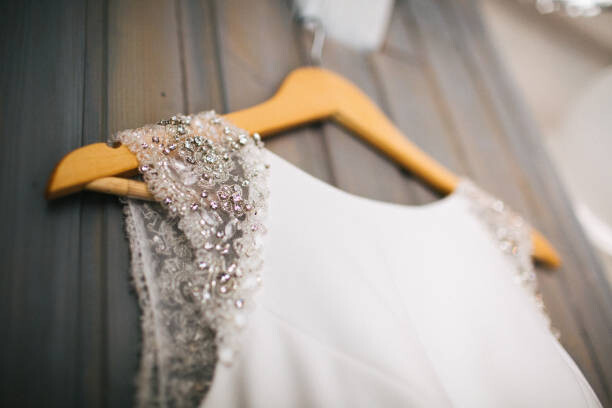 Obraz na plátně Elegant wedding dress hanging on gray wall