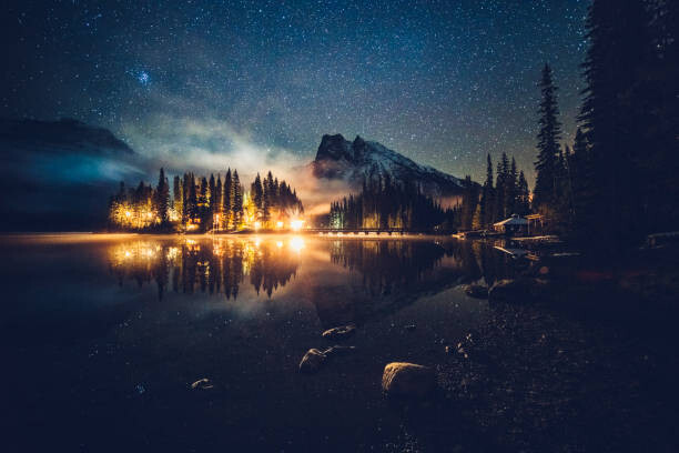 Obraz na plátně Emerald lake with illuminated cottage under