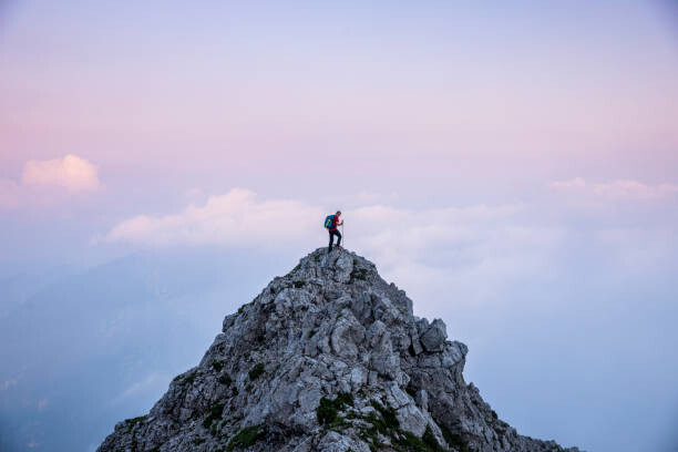Obraz na plátně Hiker man on the top of mountain during twilight