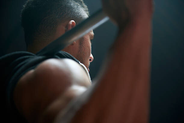 Obraz na plátně Male athlete lifting weight bar black background