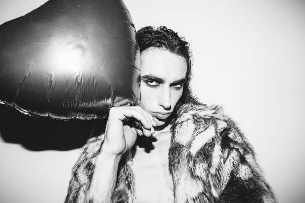 Obraz na plátně Young fashionable man with a heart shape balloon